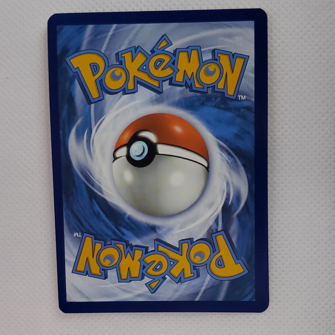 A Pokémon trading card featuring the classic blue back design with a Pokéball illustration and yellow 'Pokémon' logo text, displayed against a white textured background.