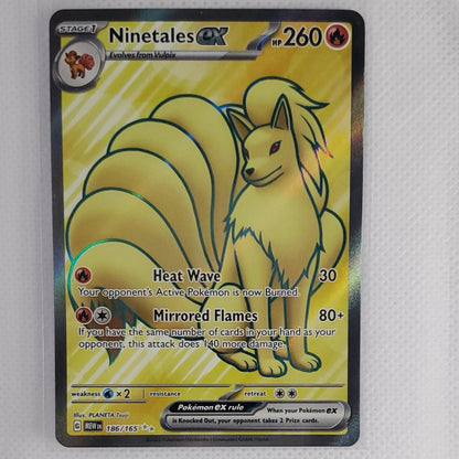 A holographic Pokémon TCG card of Ninetales, showing its yellow and black artwork, resting on a white textured surface.