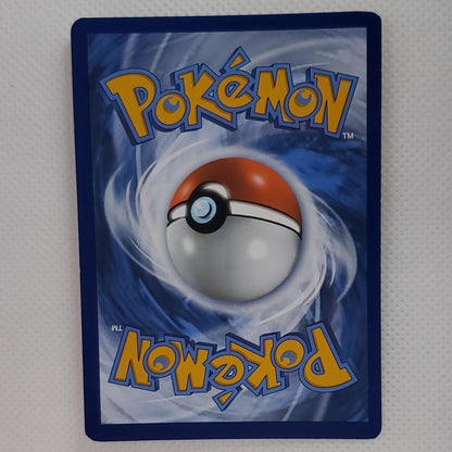 A single Pokémon trading card standing upright against a light gray textured backdrop, with a small white star-shaped object below it. The card shows the blue Pokémon logo and a red-and-white ball graphic.
