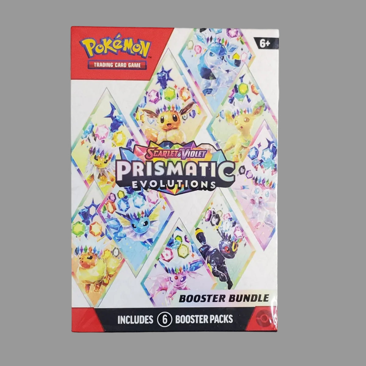 Pokémon TCG Prismatic Evolutions Booster Bundle box shown on a light gray surface. The front of the box features colorful illustrated card art and the Pokémon and TCG branding.