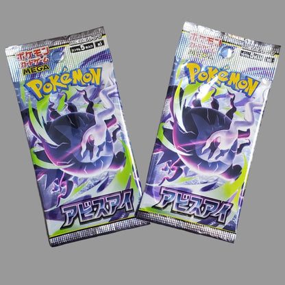Two Japanese Pokémon booster packs with a purple-and-black character design and green accents, placed on a light beige floor.