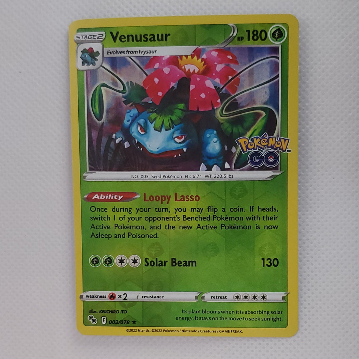 A single Pokémon trading card featuring Venusaur, displayed upright on a white surface against a white fabric background.