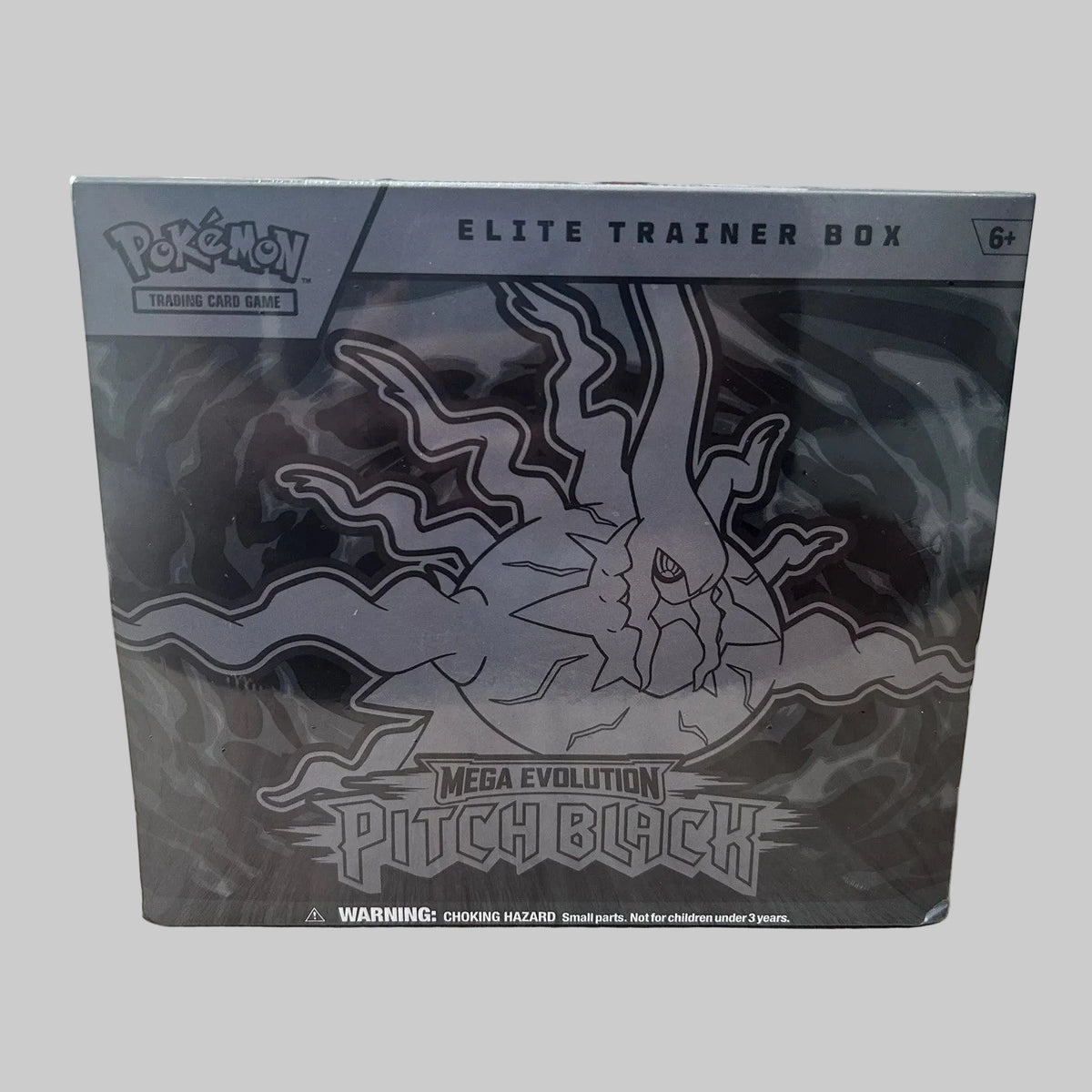 A sealed Pokémon Elite Trainer Box for Mega Evolution Pitch Black, shown in its original packaging on a light wood tabletop with a blurred indoor background.