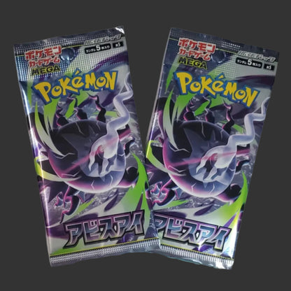 Two Japanese Pokémon booster packs, purple and green color scheme with Japanese letters.  on a charcoal backdrop