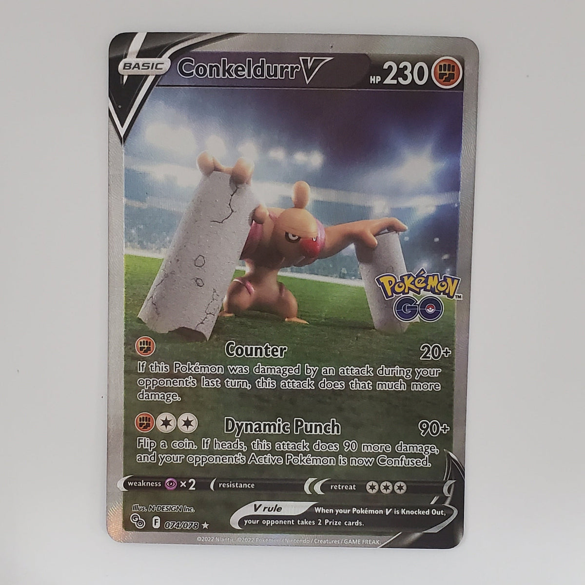 A single Pokémon trading card for Conkedure V is photographed standing upright against a plain white background. The card shows artwork of the Pokémon and game text, with visible Pokémon branding in the top right.