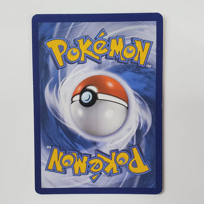 A Pokémon trading card featuring the classic blue background, yellow 'Pokémon' logo, and a red-and-white ball illustration, photographed against a white wall above a desk.