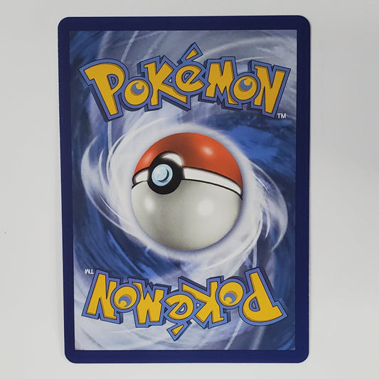 A Pokémon card featuring the classic red and white ball design on a blue background with yellow 'Pokémon' lettering, photographed against a plain white wall.