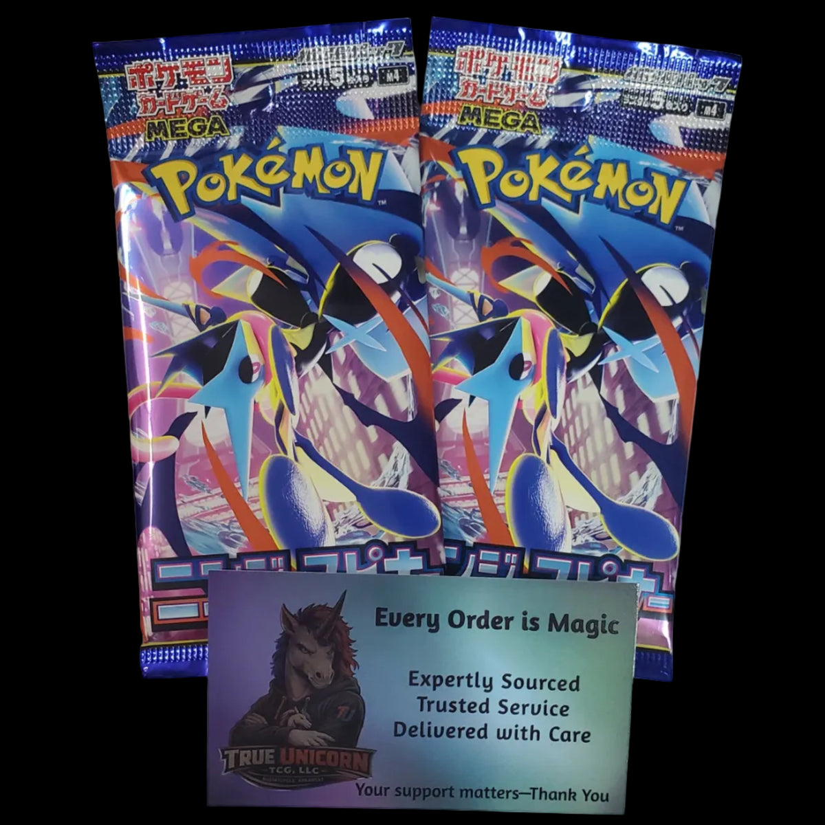 Two packs of Pokémon TCG 2025 Mega Booster Packs displayed on a white desk next to a True Unicorn support card.