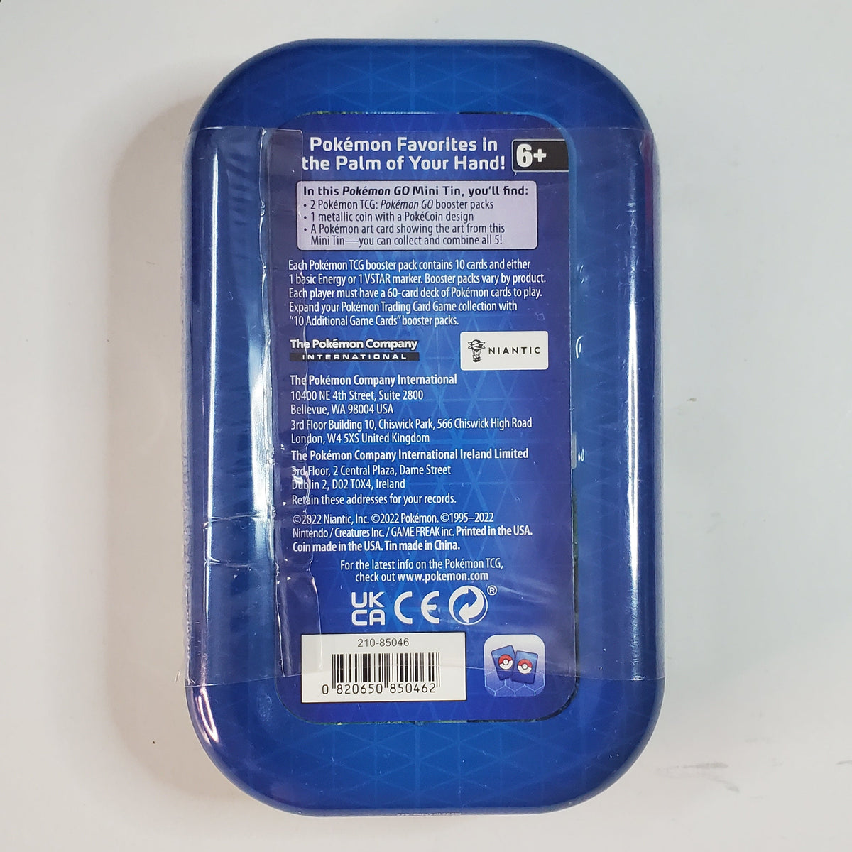 The back of a blue plastic container with a clear plastic wrap, featuring product information labels, photographed on a light gray background.